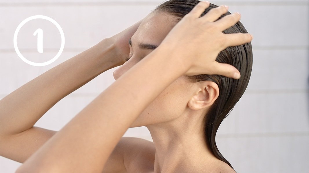 Frau unter der Dusche streicht durch ihr Haar
